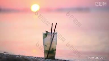 在日落时分，一杯莫吉托酒精鸡尾酒站在热带海滩的沙滩上